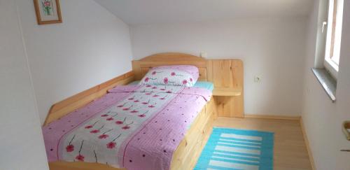a small bedroom with a bed with a purple comforter at Apartment Pri Vrtnici in Šmartno ob Paki