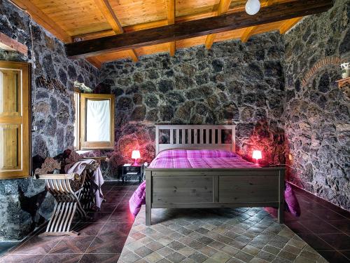 a bedroom with a bed in a stone wall at Fontana del Cherubino in Santa Maria di Licodia