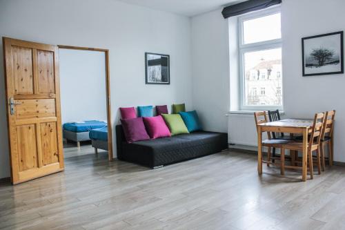 sala de estar con sofá negro y almohadas coloridas en Apartamenty Babina en Kalisz