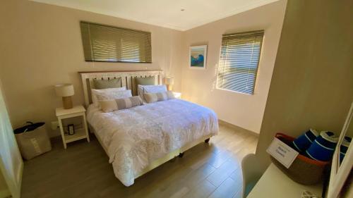 a bedroom with a bed and two windows at Maitlands Cottage in Port Elizabeth