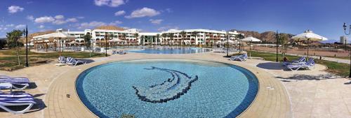 a large swimming pool with chairs and a resort at Movenpick Taba Resort & Spa in Taba