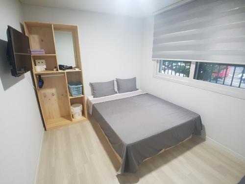 a small bedroom with a bed and a television at Yong Stay in Jeju