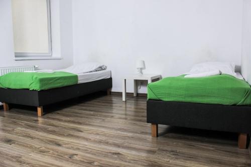 two beds with green sheets in a room at Pokoje Babina in Kalisz