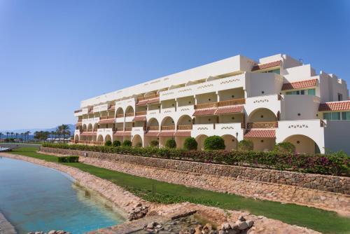 a large building next to a body of water at Movenpick Taba Resort & Spa in Taba