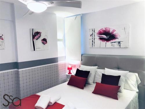 sypialnia z białym łóżkiem z czerwonymi i czarnymi poduszkami w obiekcie My Sweet Red Apartment w mieście Benidorm
