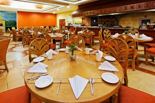 a dining room with a wooden table and chairs at Holiday Inn Merida by IHG in Mérida