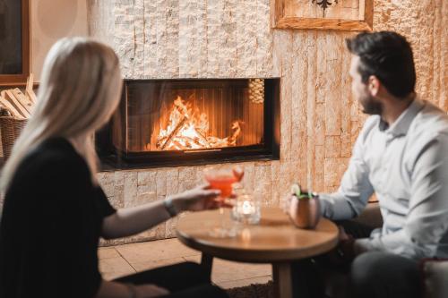 a man and woman sitting at a table in front of a fireplace at Alpine Resort Goies Superior in Ladis