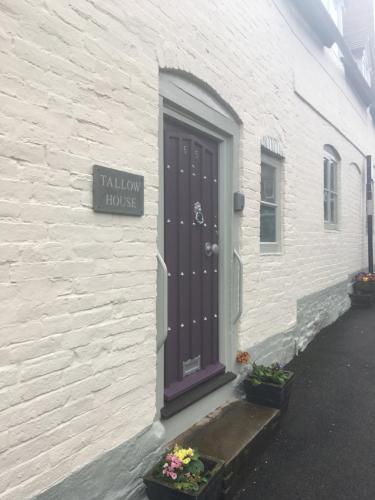 a white building with a door and a sign on it at Tallow House in Ludlow
