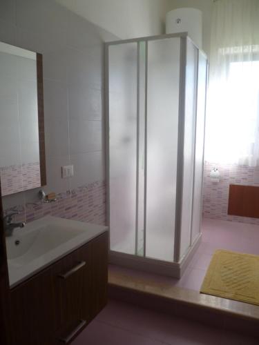 La salle de bains est pourvue d'une douche en verre et d'un lavabo. dans l'établissement LA FINESTRA SUL MARE, à Trappeto