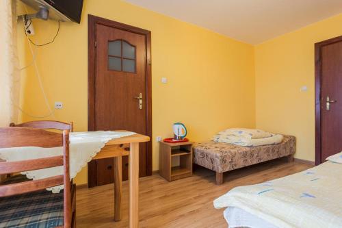 a room with two beds and a table and a door at POKOJE u JÓZKA in Polańczyk