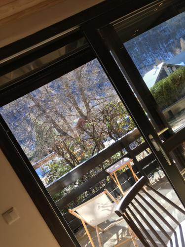 una finestra in una stanza con una sedia e un albero di Ambiance petit chalet a La Salle-les-Alpes