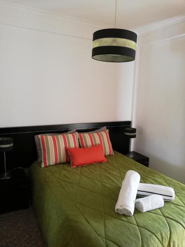 a bedroom with a green bed with towels on it at Quinta dos Carvalhais - Serra da Estrela in Fornos de Algodres