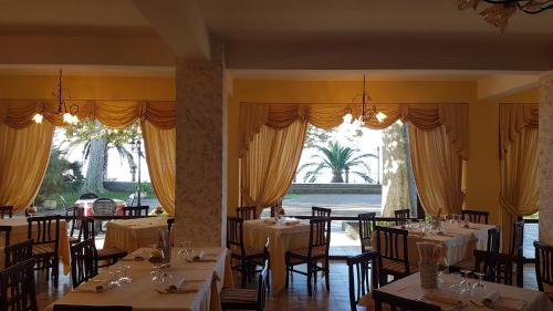 a dining room with tables and chairs and windows at Hotel Eden Sul Lago in Bolsena