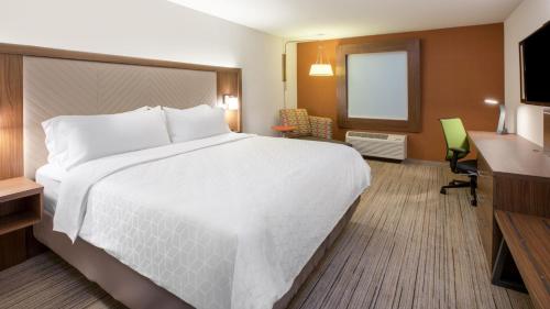 a hotel room with a large white bed and a desk at Holiday Inn Express Greensburg by IHG in Greensburg