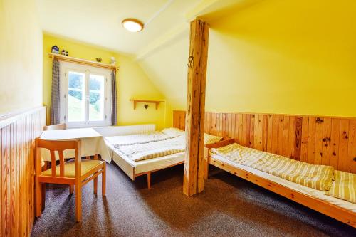 ペツ・ポト・スニェシュコウにあるChata Šohajkaのベッド2台、テーブル、窓が備わる客室です。