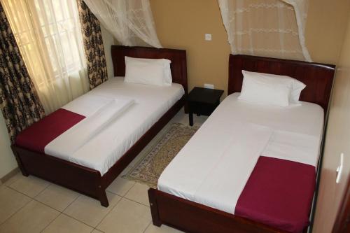 two beds in a small room with at Apricot Guest House Annex in Muyenga 