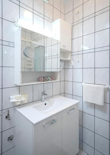 a white bathroom with a sink and a mirror at Apartment Nela Kalina in Jelsa
