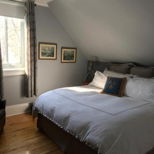 a bedroom with a large white bed with a window at La Belle aux Berges in Saint-Denis-sur-Richelieu