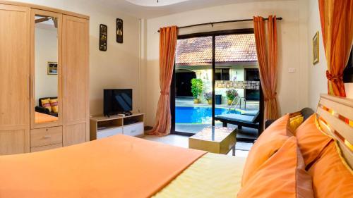 a bedroom with a bed and a television and a pool at Coconut Paradise Villas in Rawai Beach