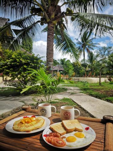 a table with two plates of food and two cups of coffee at Native House Resort powered by Cocotel in Moalboal