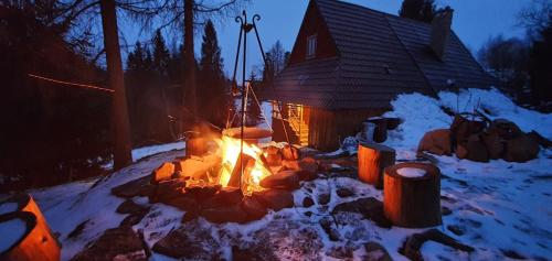uma fogueira na neve em frente a uma casa em Bacówka w sercu gór - dom z bali w Gorcach em Łopuszna