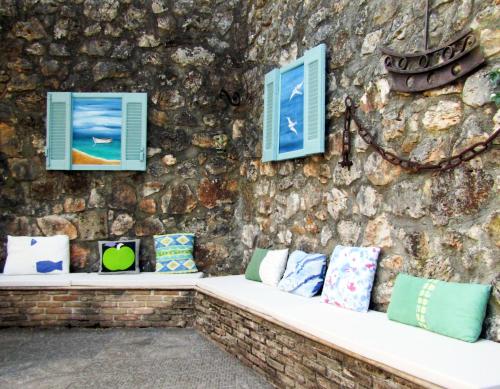 a wall of pillows on a bench against a stone wall at Polytropon Apartments in Kástron