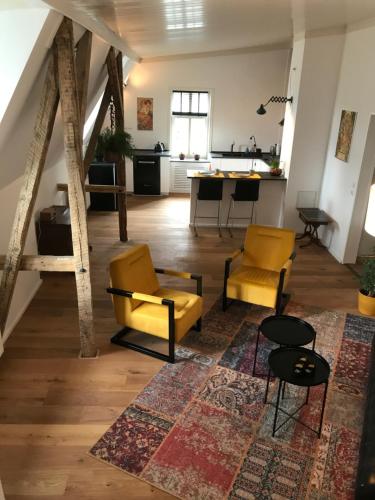 a living room with yellow chairs and a kitchen at Spinnerei in Spechtholzhock