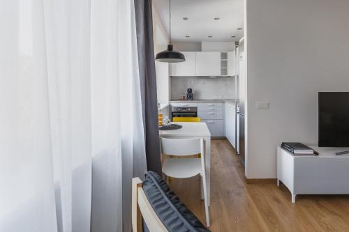 eine kleine Küche mit einer weißen Theke und einem Tisch in der Unterkunft Sun City Apartment in Šiauliai
