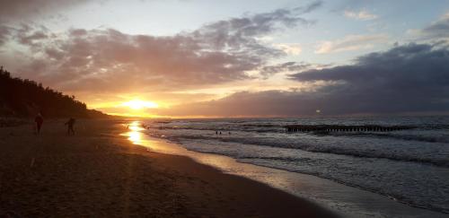 a person walking on the beach at sunset at Azalia 32 Mielno l in Mielno