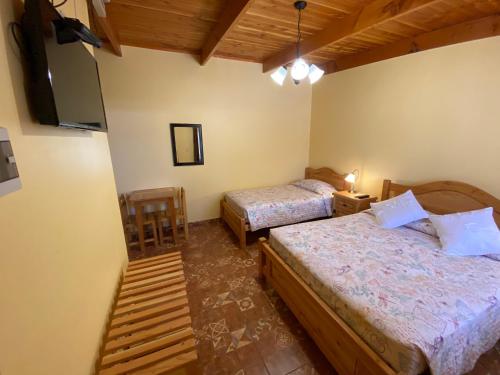 a bedroom with two beds and a flat screen tv at Las Cornizas de Catarpe in San Pedro de Atacama