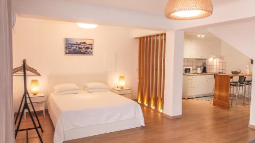 a bedroom with a white bed and a kitchen at Beija Mar in Vila Franca do Campo