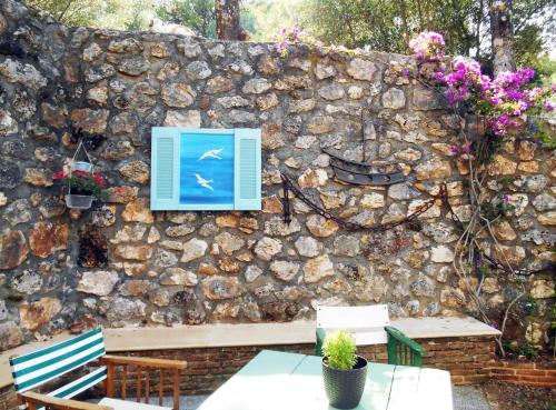 a stone wall with benches and a blue window at Polytropon Studio ground floor in Kefallonia
