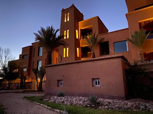 a building with palm trees in front of it at Kasbah Tamsna in Ouarzazate