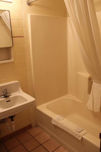 a bathroom with a sink and a tub and a toilet at Economy Inn Safford in Safford