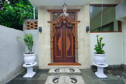 a front door of a house with two potted plants at Zamzam anjani villa in Praya