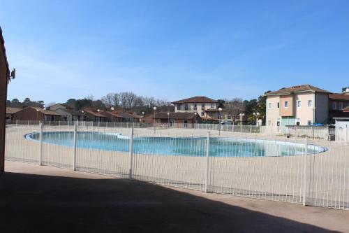 une clôture autour d'une piscine avec des maisons en arrière-plan dans l'établissement MAISON les ARCADES, à Soustons