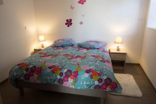 - une chambre avec un lit avec une couette à fleurs et 2 lampes dans l'établissement Chez Emilie & Charles Classé 4 étoiles, à Hunawihr