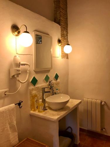 a bathroom with a sink and a mirror and lights at al-qandil in Margarida
