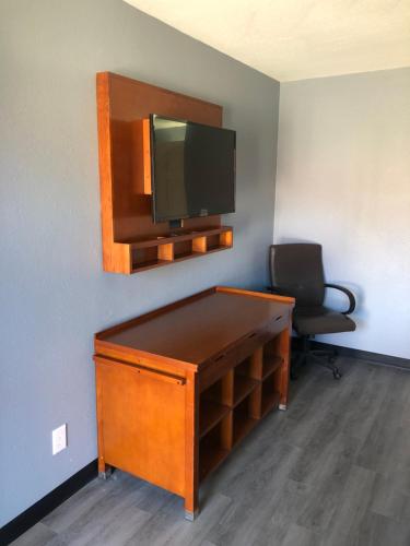 een kamer met een bureau, een tv en een stoel bij EVERKLEEN Motel Downtown in San Antonio
