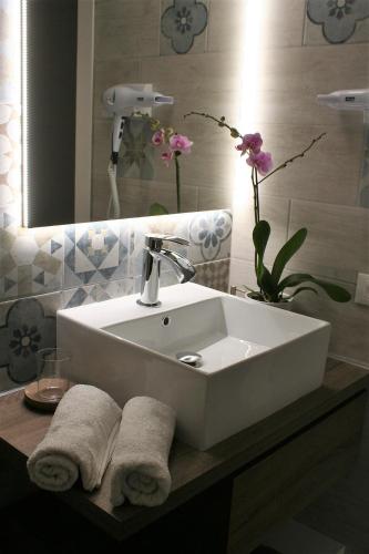 ein Badezimmer mit einem Waschbecken, einem Spiegel und Blumen in der Unterkunft Casa Ciarì in Tremosine sul Garda