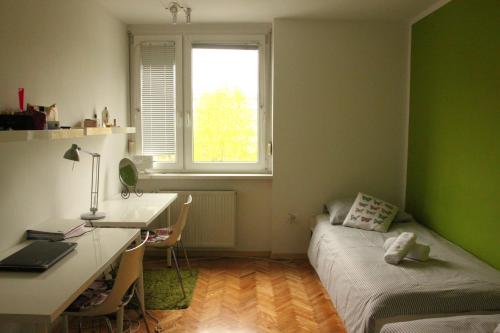 1 dormitorio con cama, escritorio y ventana en HAPPY & COSY place, Via Trieste, en Liubliana