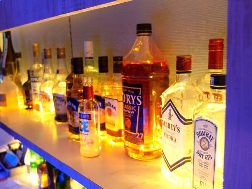 a shelf with many bottles of alcohol on it at TOP EDGE HOSTEL Koenji in Tokyo
