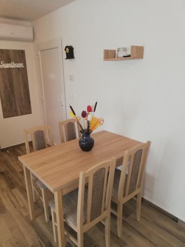 a dining room table with a vase of flowers on it at Villa Katalino in Gyenesdiás