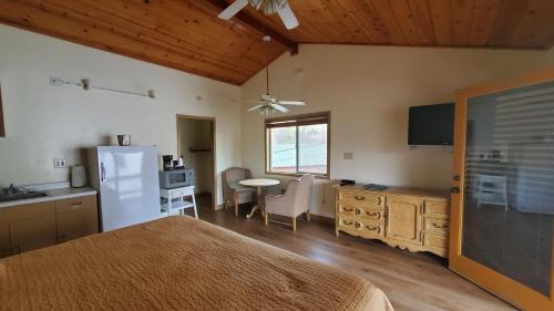 Schlafzimmer mit einem Bett, einem Kühlschrank und einem Tisch in der Unterkunft Kernville Inn in Kernville