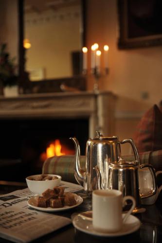 a tea kettle and cups on a table with a fireplace at Ballathie House Hotel in Perth
