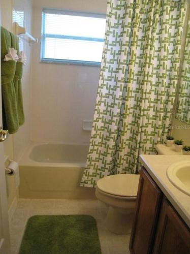 a bathroom with a tub and a toilet and a shower curtain at Family Vacation Home With Pool and Spa Near Disney and Universal in Orlando