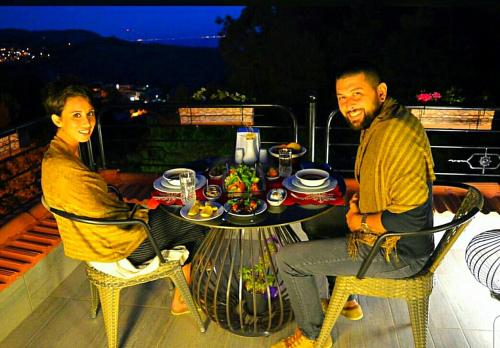 a man and woman sitting at a table on a balcony at Kazdaglari Karye Müze Hotel in Kucukkuyu