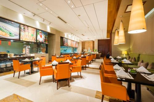 uma sala de jantar com cadeiras e mesas cor de laranja num restaurante em Crowne Plaza Xiangyang, an IHG Hotel em Xiangyang