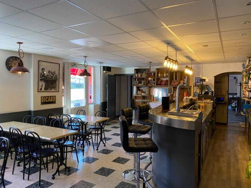 un restaurante con mesas y sillas y un bar en Hôtel Etape, en Les Omergues