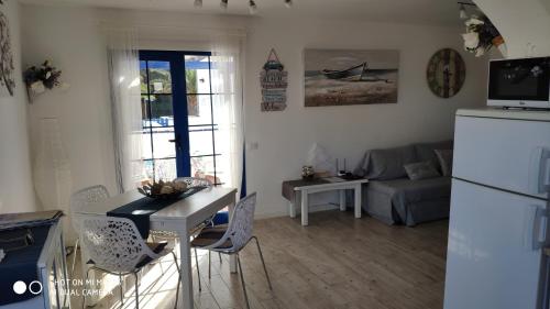 een keuken en een woonkamer met een tafel en een koelkast bij Appartamento Delia in Caleta De Fuste